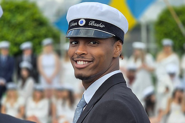 Mörk kille som i studentmössa och kostym